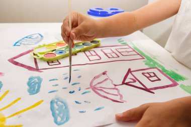 Child drawing a picture by watercolor, back to school concept