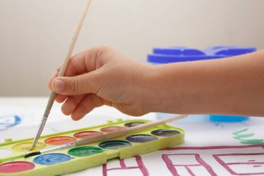 Child drawing a picture by watercolor, back to school concept