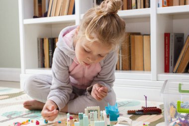 Çocuk inşaatçı tuğlalarıyla, oyuncaklarla oynar, yumuşak odaklı arka planla çalışır