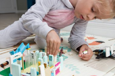 Çocuk inşaatçı tuğlalarıyla, oyuncaklarla oynar, yumuşak odaklı arka planla çalışır