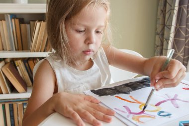 Little child draws with watercolor, concept of education in the kindergarten, soft focus background