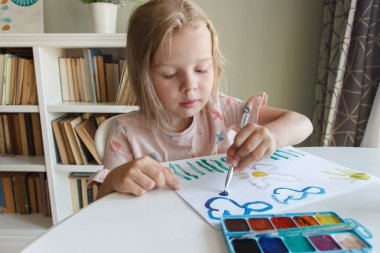 Little child draws with watercolor, concept of education in the kindergarten, soft focus background