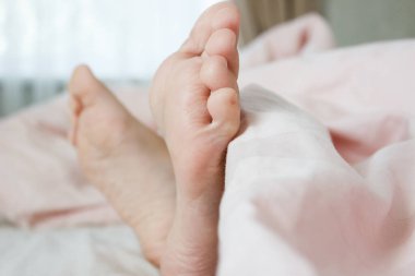 Ayaklar hafif bir battaniyenin altında, yumuşak bir odak arka planı var. Sağlıklı yaşam kavramı