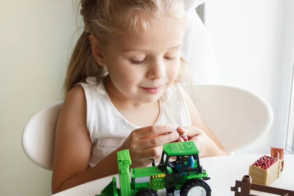 かわいい子供は農具のおもちゃで遊んでいる ビジネスや農業のコンセプト ぼやけた背景 — ストック写真