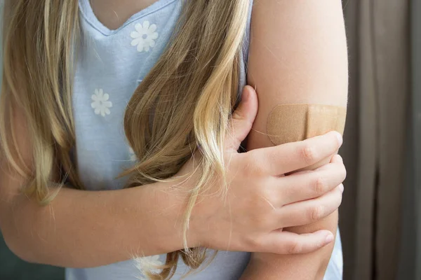 Maskeli küçük bir kız derisi alçılı bir kolu tutuyor. Aşı ve bağışıklık kavramı