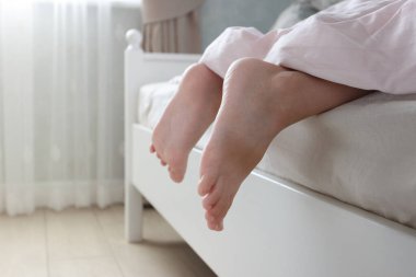 Ayaklar hafif bir battaniyenin altında, yumuşak bir odak arka planı var. Sağlıklı yaşam kavramı