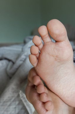 Ayaklar hafif bir battaniyenin altında, yumuşak bir odak arka planı var. Sağlıklı yaşam kavramı