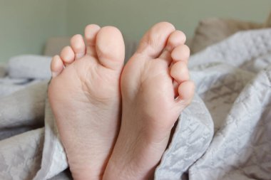 Ayaklar hafif bir battaniyenin altında, yumuşak bir odak arka planı var. Sağlıklı yaşam kavramı