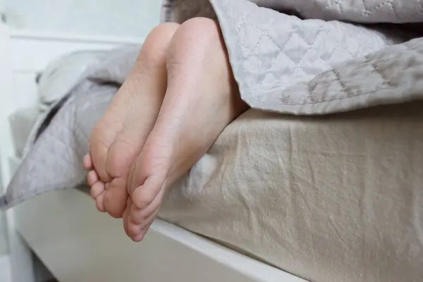 Πόδια Κάτω Από Μια Ελαφριά Κουβέρτα Στο Κρεβάτι Μαλακό Φόντο Εικόνα Αρχείου
