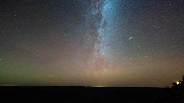 Samanyolu 'nun zaman geçişi yıldızlı bir gecede süzülüyor, sayısız yıldız parıldıyor, kozmik bulutlar zarifçe hareket ediyor, göksel güzellik, uyuyan yeryüzünün üzerinde huzur dolu bir karanlığa bürünüyor.