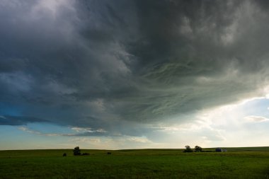 Güzel yeşil tepeler yağmur şeritlerinin altında oturur çarpıcı bir kontrastla, karamsar atmosferle, gölgelerle ve dokularla harmanlanan doğayla güzellik ve hava durumu gücüyle.