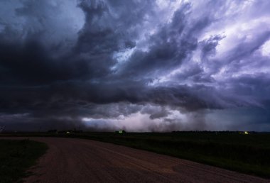 Yıldırımlar devasa bir fırtına bulutunu aydınlatıyor, dramatik dokusunu, derin gölgesini ve kasvetli gökyüzünü ortaya çıkarıyor, yoğun güzelliği, tehlikeyi ve doğa koşullarının destansı gücünü yakalıyor.