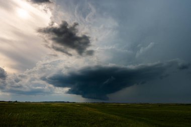 Dönen fırtına bulutları ve sağanak yağış yaklaşan şiddetli hava sinyalleri, hareketli, gölge, doku ve karamsar atmosfer ile dolu dramatik bir gökyüzü, doğa gücü ve güzelliği yakalıyor.