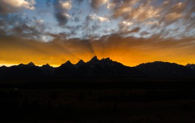 Göz kamaştırıcı günbatımı renkleri gökyüzünü mükemmel bir dağ siluetinin üzerinde dolduruyor, dramatik, renkli bir bulut yaratıyor, gölge ve dokularla, doğanın destansı güzelliğini ve vahşi manzarayı gözler önüne seriyor.