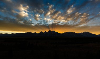 Gün batımındaki renkli ışık ışınları panoramik bir dağ sahnesini süpürüyor. Yumuşak dokusu, gölgesi ve manzaralı güzelliğiyle dramatik bir gökyüzü yaratıyor. Doğanın ve vahşi doğanın huzur dolu özünü yakalıyor.