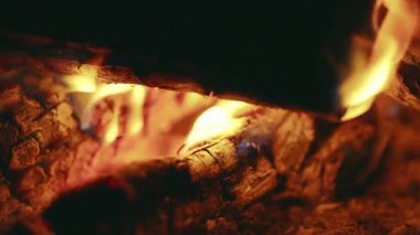 Dışarıdaki kamp ateşi kütüklerinden gelen titreyen alevlerin yakın çekimi, sıcaktan, dumandan ve yanan odunlardan parlayan parlaklığı, geceleri doğada sıcak ve rahatlatıcı bir sahne yaratır.