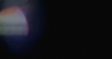 Koyu arkaplanda gökkuşağı renkleri olan bulanık bir lens aydınlatma efekti. Soyut ve desenli.