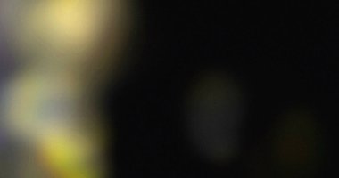 Karanlık arkaplanı olan bulanık bir görüntü. Sarı ve yeşil ışık bokeh efektleri görünür.