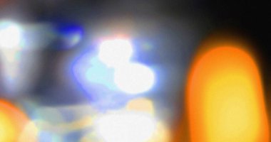 Geceleri bulanık şehir ışıkları turuncu mavi ve beyaz bokeh efektlerini gösteriyor. Işık sızıntılı soyut fotoğrafçılık.