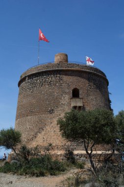 Soller, Balear Adaları, İspanya - 13 Mayıs 2024: Kulenin tepesinde iki bayrakla eski gözetleme kulesi Torre Picada 'ya yaklaşırken bir manzara.