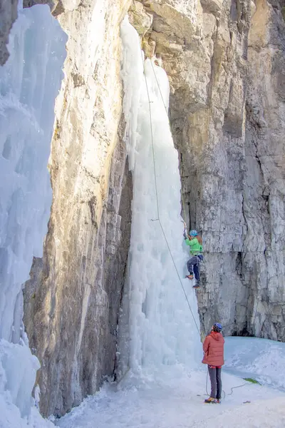 Canmore, Alberta Canada - 22 Ocak 2022: Sıcak bir kış gününde Grotto Kanyonu 'nda şelaleye tırmanan bir kadın. Dağcıların yeteneklerini geliştirmeleri için bir eğitim yeri..