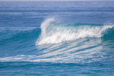 Kristal berrak turkuaz mavi su renginde dalgalar eziyor.