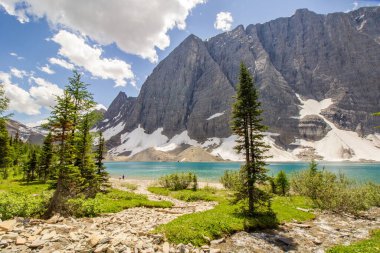 Kootenay Ulusal Parkı, British Columbia, Kanada - 07 / 01 / 2023: İki yürüyüşçü hedeflerine ulaştıktan sonra mola verdiler, kayalık dağlardaki Floe Gölü 'nün deniz mavisi suları