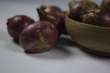 Beyaz arka planda ahşap kasede soğanlar