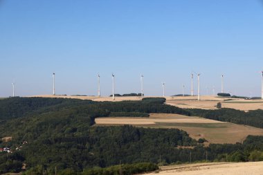 Almanya 'nın kırsal kesimindeki bir tepenin üstünde rüzgarda dönen değirmenler.