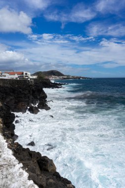 Idyllic scene of clear blue sea crashing against volcanic black rocks along the cliffs of Terceira Island, Azores. clipart