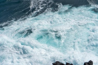 Idyllic scene of clear blue sea crashing against volcanic black rocks along the cliffs of Terceira Island, Azores. clipart
