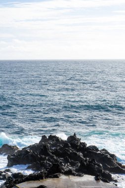 Güçlü dalgalar, Azores, Terceira Adası 'nda manzaralı bir banyo alanı olan Cinco Ribeiras kıyısı boyunca çarpışıyor..