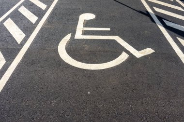Yere engelli park levhası çizilmiş. Özürlü kişiler için ayrılmış park yerini simgeliyor. Erişilebilirlik ve dahil olma kavramı.