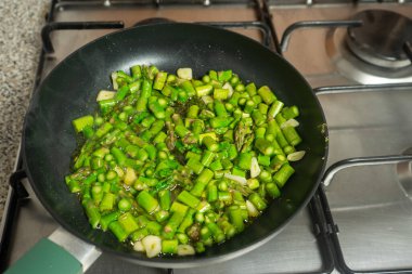 Taze yeşil kuşkonmaz doğranmış ve tavada cızırdıyor..
