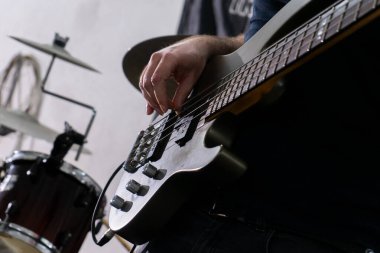 Sıradan bir ortamda bas gitar çalan bir adam. Enstrümanına odaklanmış, parmakları tellerin üzerinde kayıyor. Rahat duruşu ve günlük kıyafetleri rahat bir müzik seansına işaret ediyor..
