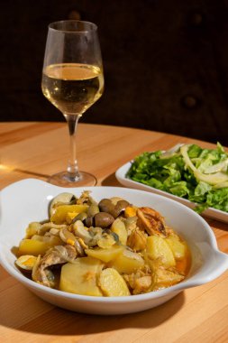 Bir tabak Bacalhau Gomes de S yanında fırında morina, patates ve soğan, üstüne de siyah zeytin ve haşlanmış yumurta. Bir bardak beyaz Alentejo şarabı ve bir restoranda salata eşliğinde..