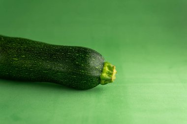 Taze bir kabak canlı yeşil bir arka plana dayanır, ince bir gölge bırakır. Pırıl pırıl, koyu yeşil teni arka planla çok güzel zıtlaşıyor çarpıcı ve uyumlu bir kompozisyon oluşturuyor..