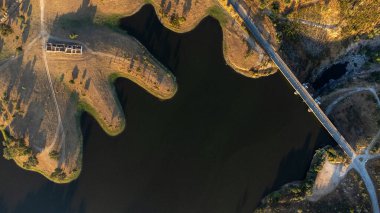 Gün batımında Vora 'daki Monte Novo Barajı' nın havadan görünüşü, sakin suları, yeşillikleri ve batan güneşin altın renklerini gözler önüne seriyor..