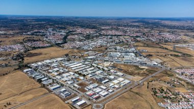 Aerial view of vora's Industrial and Technological Park showcasing modern facilities, green spaces, and infrastructure against a backdrop of the historic city's landscape. clipart