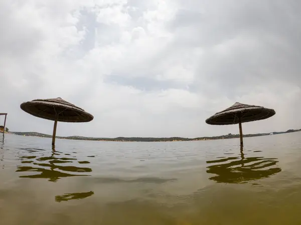 stock image Straw sunshades submerged in water at Azenhas DelRei beach, Alqueva Dam, nearly at full capacity due to heavy winter rains.