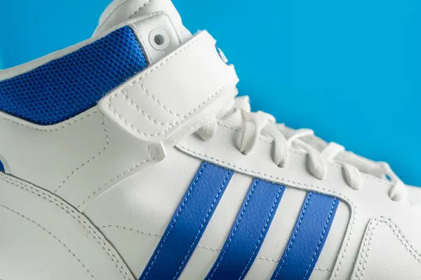 Stock image vora, Portugal. March 3, 2024. Adidas white and blue basketball sneakers on a matching blue background, showcasing sleek design and sporty style.