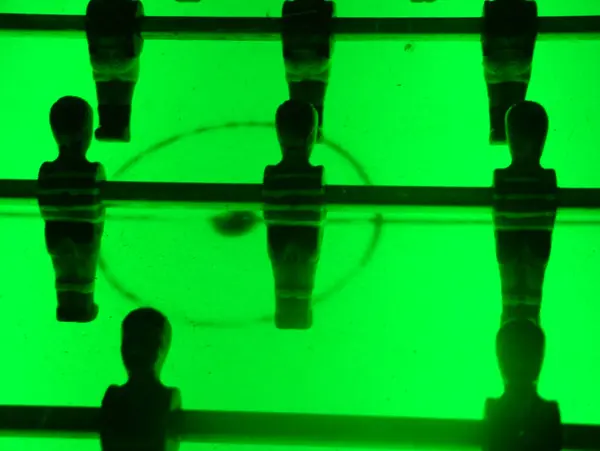 stock image A retro-illuminated foosball table with a vibrant green glow creates an energetic and nostalgic atmosphere, perfect for adding a playful touch to any setting.