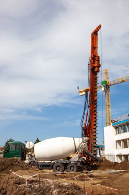 Çok işlevli bir sondaj kulesi bir inşaat sahasında vinç arasında duruyor, sanayi gücünü ve kentsel gelişimin arka planına karşı mühendislik hassasiyetini gösteriyor..