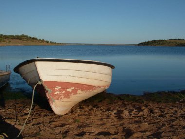 Portekiz 'in Alentejo şehrindeki sakin kıyılara yanaşan sakin bir tekne engin mavi sulara ve arka planda bereketli manzaralara sahipti..