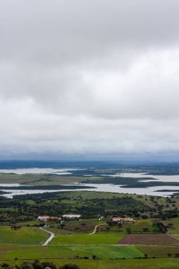 Monsaraz 'dan gelen Alqueva Barajı' nın manzarası. İspanyol toprakları bir sonbahar öğleden sonrasında arka planda. Yumuşak bir gökyüzünün altında suyu ve toprağı harmanlayan sakin, geniş bir manzara..