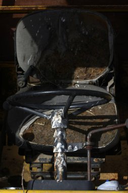 Terk edilmiş bir kepçe yükleyici kokpitine yakın çekim, aşınmış kontrolleri ve solmuş kadranları gösteren, ihmal ve endüstriyel bozulma hissi yakalayan.