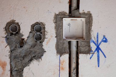 Elektrik bağlantı kutusu inşaat alanının duvarına monte edilmiş, kapağı açık ve elektrik kablolarının kurulmasını bekliyor..