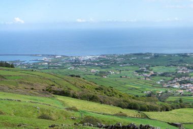 Asor 'ların yemyeşil alanları, temiz bir gökyüzünün altında düzgün dikdörtgen şekiller oluşturan taş duvarlarla bölünmüş. Adaların doğal güzelliğini ve eşsiz tarımını gösteren sakin bir manzara..