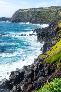 Atlantik Okyanusu dalgaları, Portekiz, Azores, Terceira Adası 'nın engebeli kıyı şeridinde volkanik kayalara çarpıyor..