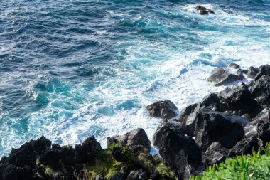 Atlantik Okyanusu dalgaları, Portekiz, Azores, Terceira Adası 'nın engebeli kıyı şeridinde volkanik kayalara çarpıyor..